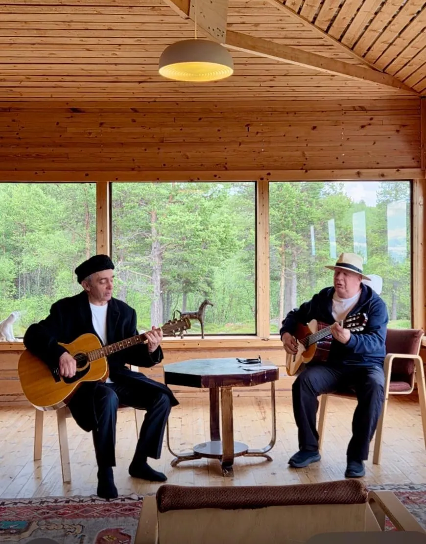 Two guitarists playing in the forest-view room at Manna BB, Lapland
